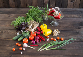 Onions, peppers, dill, tomatoes, cucumbers, radishes, dill, rucola and mushrooms on a wooden dark background