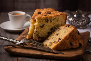 cup of coffee and slices of home made cake with raisins on wooden plate