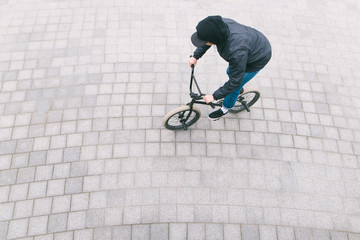 A man rides a BMX bike on a pavement. View of a cyclist on top. Freestyle on BMX. BMX Concept.