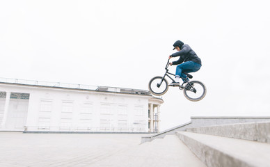 Freestyle on BMX. A young man jumps on the BMX from the stairs against the backdrop of a...