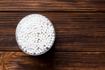 Container with cotton sticks on a wooden background. Personal hygiene, body, hygiene
