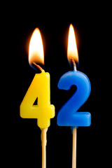 Burning candles in the form of 42 forty two (numbers, dates) for cake isolated on black background. The concept of celebrating a birthday, anniversary, important date, holiday, table setting