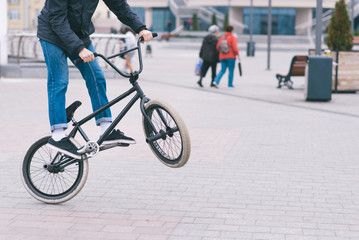 BMX freestyle. Young man doing tricks in a park on a BMX bike. The cyclist trains on the back wheel...
