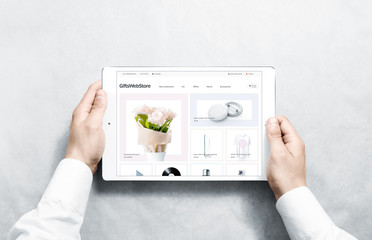 Hands holding tablet with gifts webstore mock up on screen, isolated. Clothing web page interface...