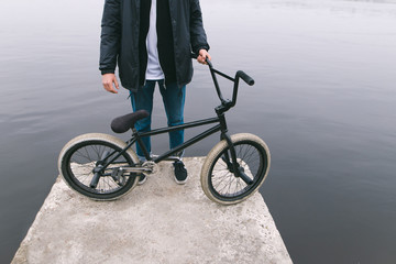 BMX rider stands on a water bike pier. Bicycle and legs on the background of the river. Walk on the bike