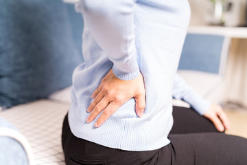 Obraz premium back pain at home. women suffer from backache. healthcare and medical concept