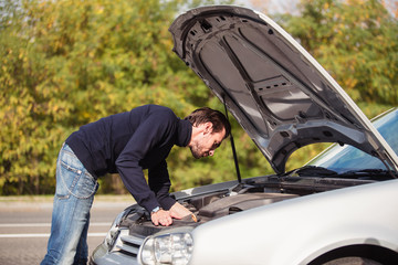 A man tries to repair the car on the road