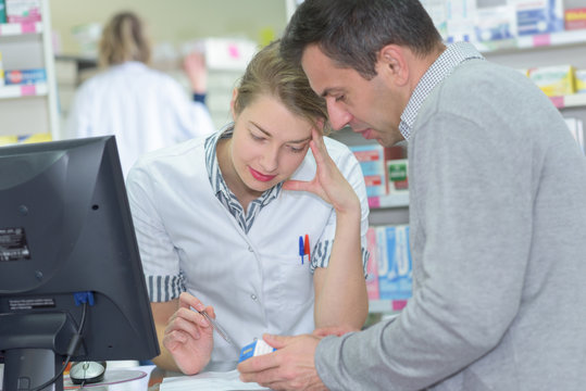 Pharmacist looking at prescription with male customer