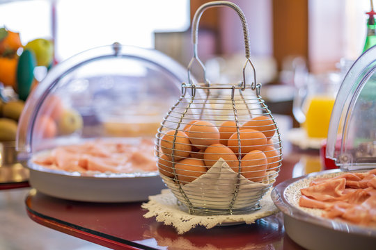 Fresh Eggs In A Wire Basket And Trays With Cold Cuts On The Table. Self-service Breakfast