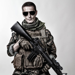 Fototapeta premium Studio shot of United States Marine with rifle weapons in uniforms. Military equipment, army helmet, combat boots, tactical gloves. Isolated on white, weapons, army, patriotism concept