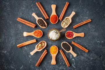 Various spices in wooden spoons  on dark stone table