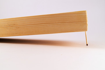 The wooden board with the processed surface is kept from falling by one thin match.