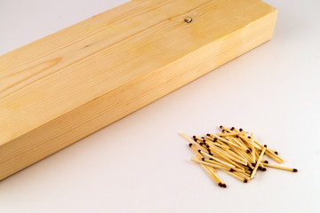 Wooden block with a processed surface, near which a hill of matches on a white background.