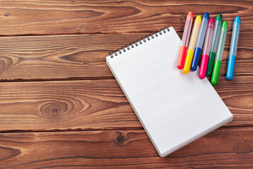 Office desk table top view. Notepad with blank pages on wooden table
