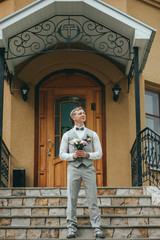 Stylish groom holding a tender pink wedding bouquet