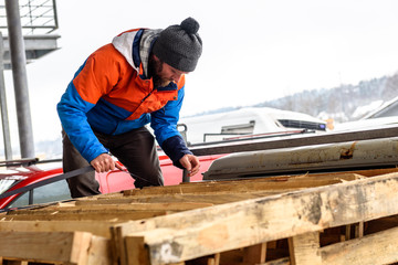 Man is loading wooden pallets on a truck in winter.