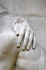 Part view of an old and weathered sculpture. Comforting hand on a shoulder.