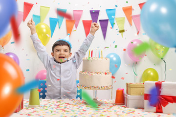 Overjoyed kid with a party hat and birthday cake