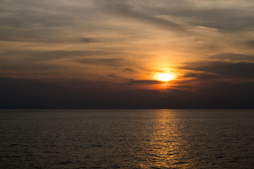 Sunset at sea with the red sky and reflection of the sun in the surface.