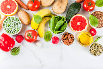 Healthy food background, trendy Alkaline diet products - fruits, vegetables, cereals, nuts. oils, white marble background above copy space