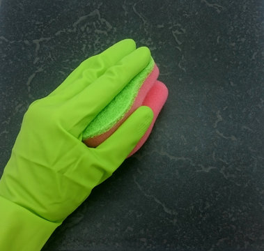 Hand im grünen Gummihandschuh mit Schwamm