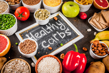 Diet food background concept, healthy carbohydrates (carbs) products - fruits, vegetables, cereals, nuts, beans, dark blue concrete background