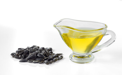 Sunflower seed oil in a glass gravy boat and a handful of sunflower seeds isolated on a white background.