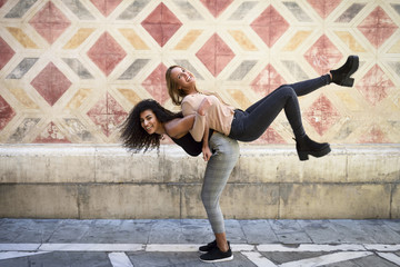 Laughing woman carrying her best friend piggyback