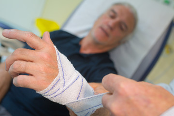 doctor bandaging hand of senior man patient