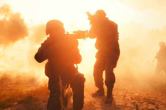 United States Marines in action. Military equipment, army helmet, warpaint, smoked dirty face, tactical gloves. Military action, desert battlefield, smoke grenades