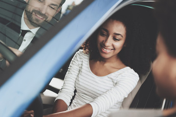 African american family at car dealership. Salesman is showing new car.