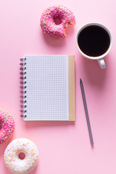 Pink and white donuts with cup of coffee and note on pink background