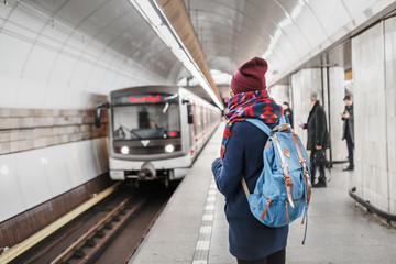 woman traveler with backpack waiting for train in subway station