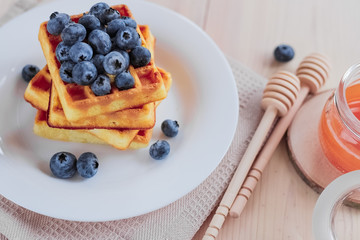 Belgian waffles with blueberries on the light wooden table. Healthy breakfast. 