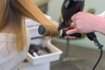 close up hairdresser drying female clients hair