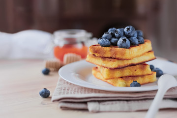 Belgian waffles with blueberries on the light wooden table. Healthy breakfast. 