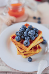 Belgian waffles with blueberries on the light wooden table. Healthy breakfast. 
