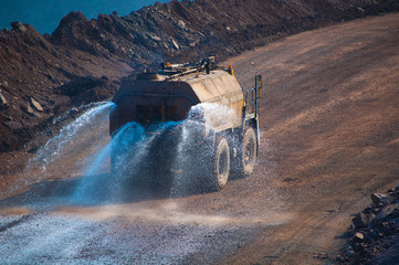 Heavy truck pours the road with water in the iron ore quarry. Dust removal, protection of the environment. Irrigation of the road from dust