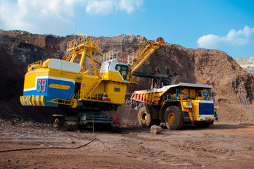 Fototapeta premium Excavator in the quarry loads the dumper with iron ore.