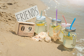 Four Mojito with a calendar from June 9, on the beach with seashells and a starfish. On the international day of friends