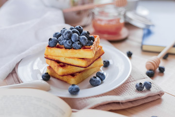 Belgian waffles with blueberries on the light wooden table. Healthy breakfast. 