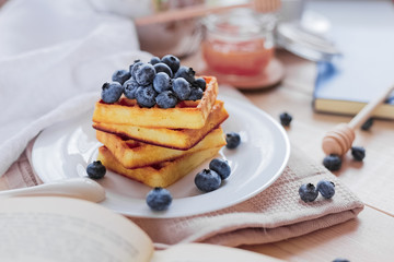 Belgian waffles with blueberries on the light wooden table. Healthy breakfast. 