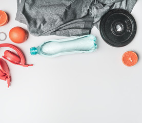 concept of sports lifestyle, headphones, dumbbells, oranges, a bottle of water, a t-shirt for training place for text flat lay