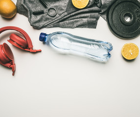 concept of sports lifestyle, headphones, dumbbells, oranges, a bottle of water, a t-shirt for training place for text flat lay
