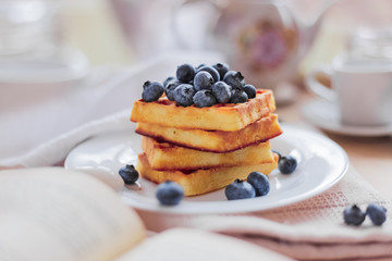 Belgian waffles with blueberries on the light wooden table. Healthy breakfast. 
