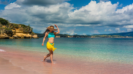 Fototapeta na wymiar Full length of a fashionable young woman enjoying happiness and freedom while walking on a tropical beach during summer vacation in Komodo Island, Indonesia