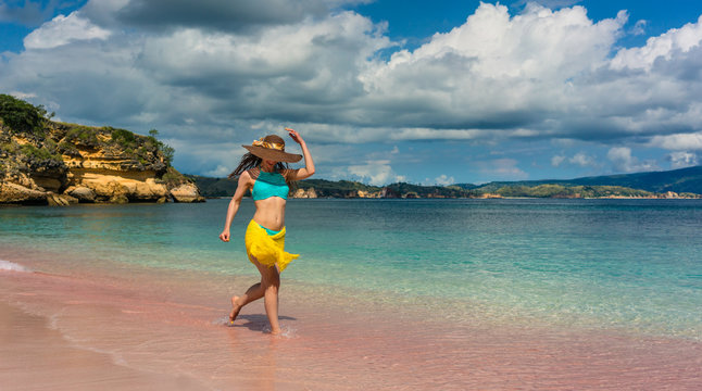 Full length of a fashionable young woman enjoying happiness and freedom while walking on a tropical beach during summer vacation in Komodo Island, Indonesia