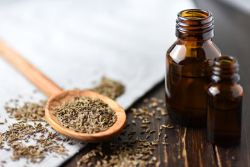caraway oil and seeds on wooden spoon and essential oil