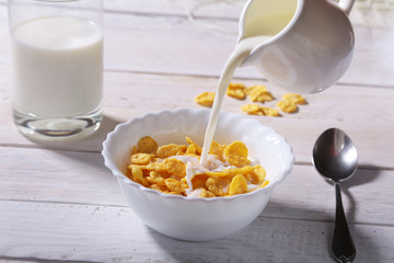 Milk pouring into a bowl of delicious corn flake cereals and cap with espresso coffee. Morning...