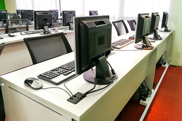 Empty computer classroom with monitors on top of table